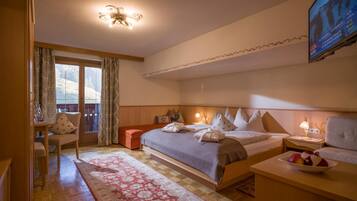 A hotel room with a bed, bedside table, chair, and a television mounted on the wall.