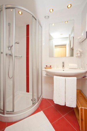 A modern bathroom with a glass-enclosed shower, a white sink, and a mirror above it.