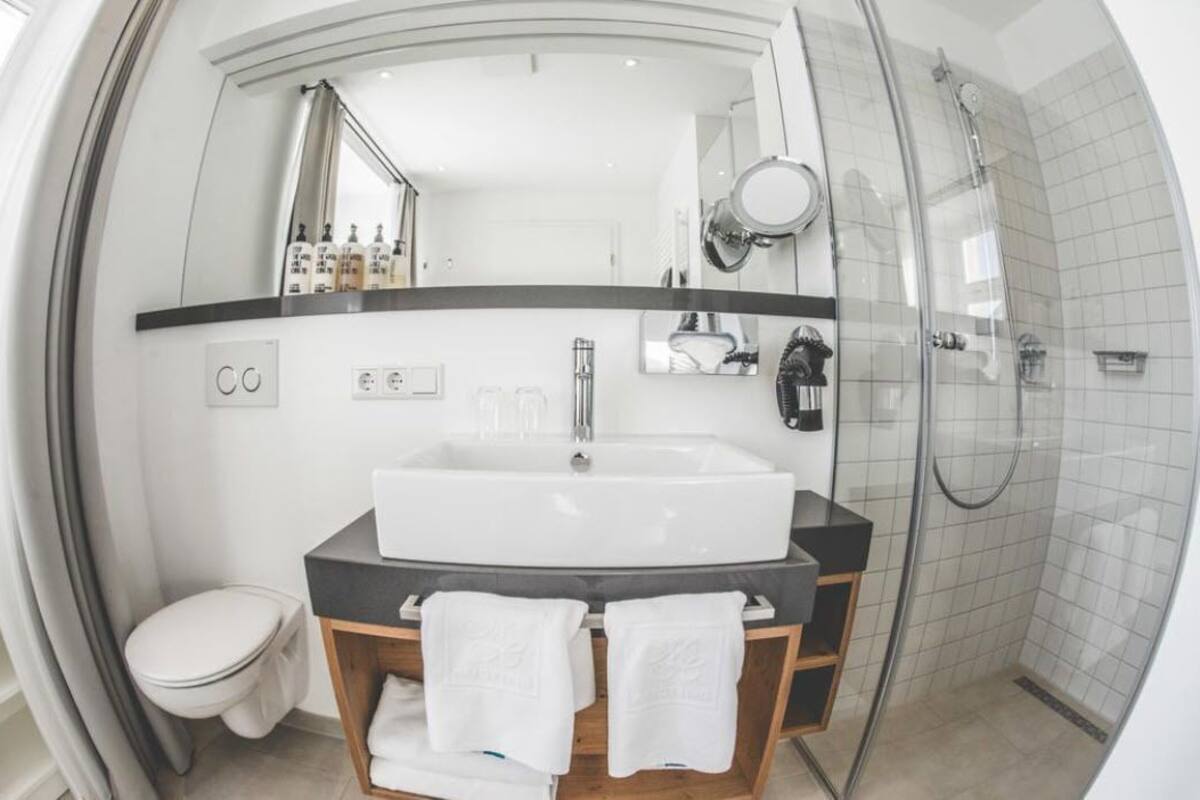 A modern bathroom with a large sink, mirror, and shower.