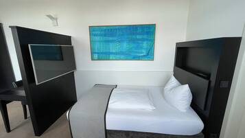 A hotel room with a bed, a desk, and a large abstract painting on the wall.