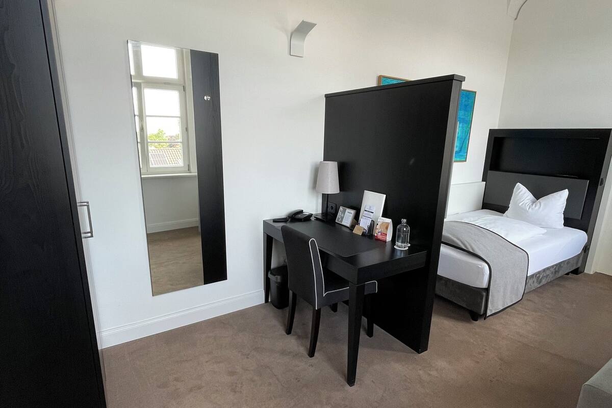 A bedroom with a bed, a desk, and a chair.
