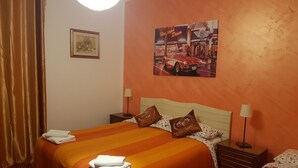 A hotel room with two beds, orange bedding, a framed picture on the wall, and a lamp on each bedside table. - B&B Magica Venezia (Mestre)