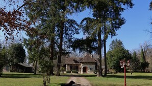 Una casa de campo con un sendero de tierra que la lleva a ella, rodeada de  árboles y un área verde.