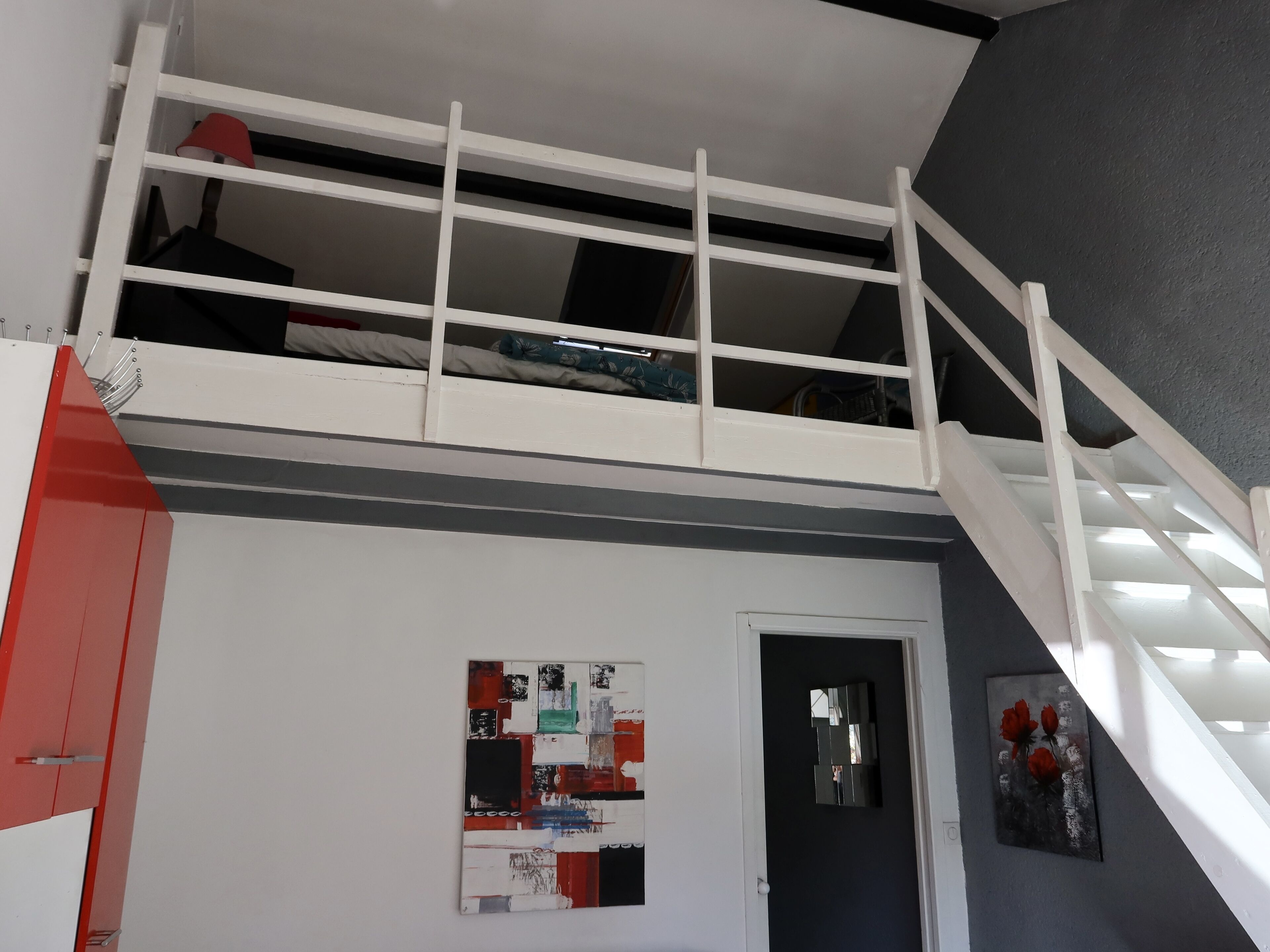 Une pièce avec un lit superposé, une porte et un mur orné d’une affiche.