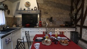 Una cocina con una mesa de comedor lista para el desayuno, que incluye pan, mantequilla y mermelada.