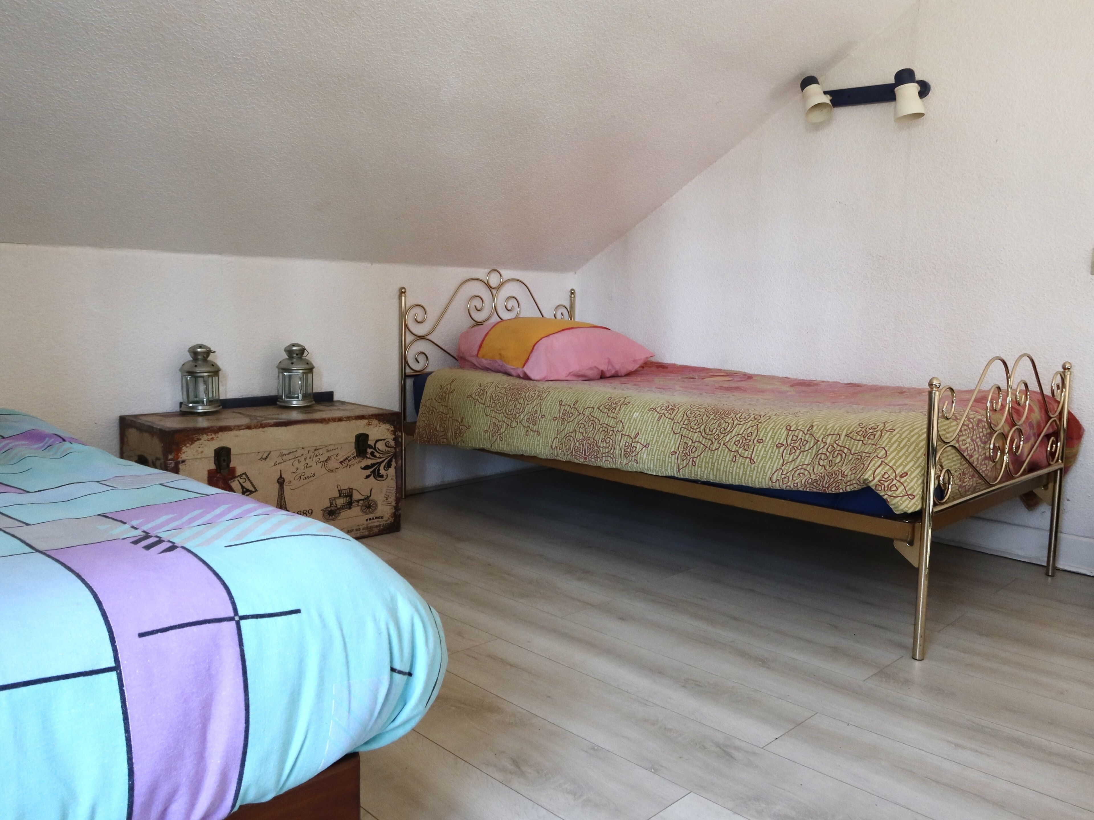 A bedroom with a single bed, a nightstand, and a small table.