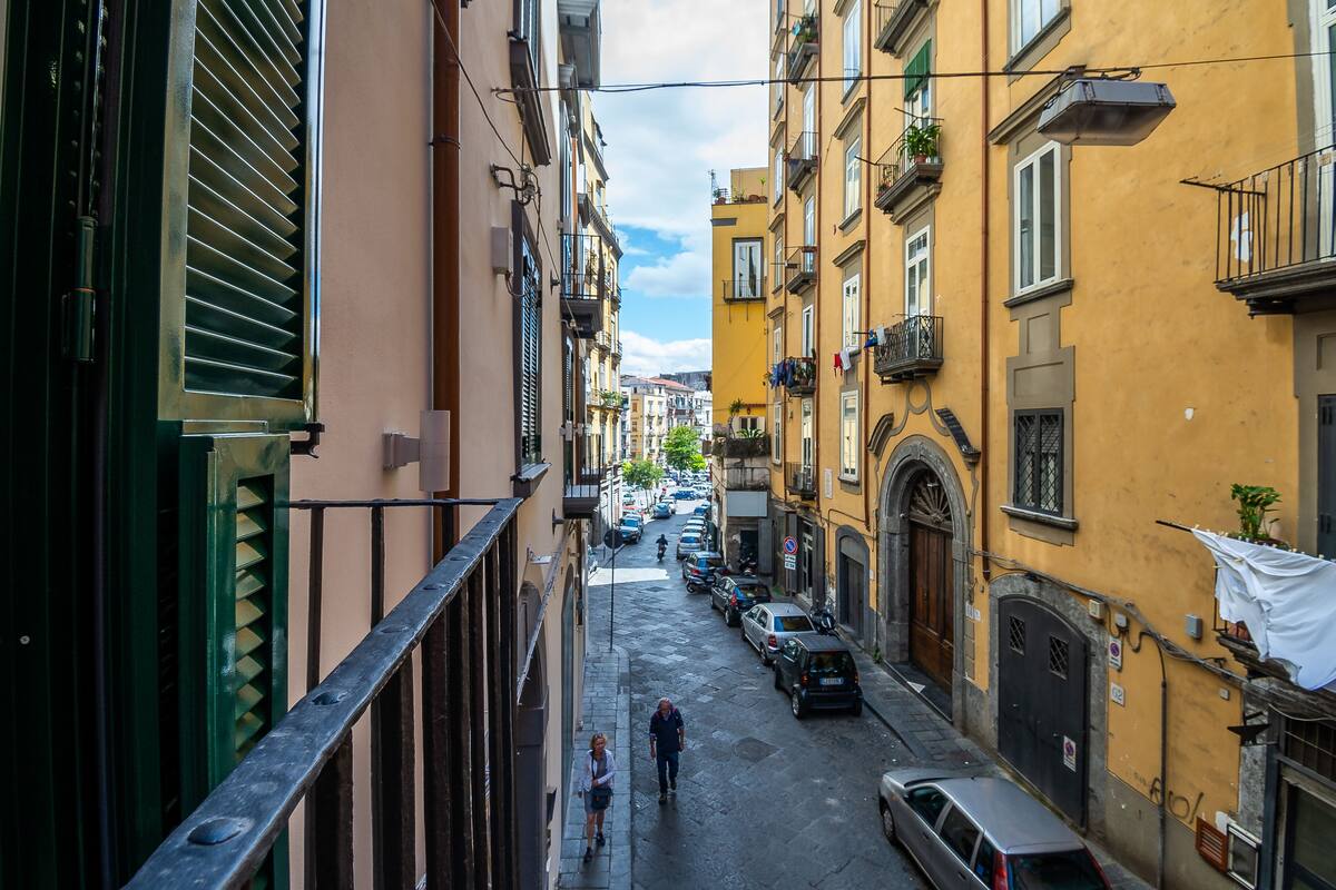 A narrow street with parked cars and buildings on both sides.