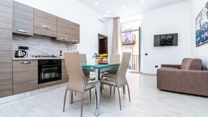 A modern kitchen with wooden cabinets, a dining table with chairs, and a living area with a sofa. - Palazzo Settembrini 49 (Naples)
