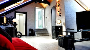 A loft-style room with a sloped ceiling, exposed wooden beams, a fireplace, a television, and a bicycle. - Palazzo Settembrini 49 (Naples)