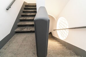 A staircase with a handrail and a light fixture on the wall. - Palazzo Settembrini 49 (Naples)