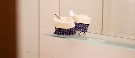 Un baño con dos espejos redondos colgados en la pared, un estante de vidrio con artículos de tocador y un lavamanos con grifo.