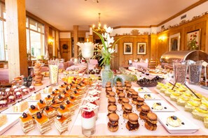 A buffet with various desserts and a central floral arrangement.