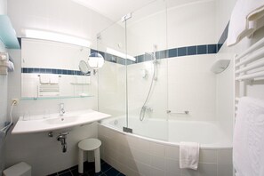 A modern bathroom with a glass-enclosed shower, a white sink with a mirror, and a bathtub.