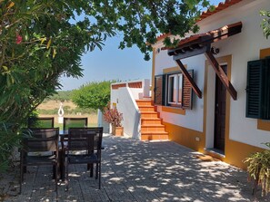 A patio with a table and chairs, a staircase, and a view of the countryside.