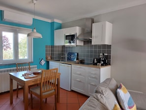 A compact kitchen with a dining table, chairs, a coffee machine, and a microwave.