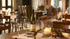 Una mesa de comedor con una botella de vino, copas y una vela.
