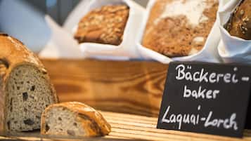 A bakery display with various types of bread and a sign indicating the bakery name and location.
