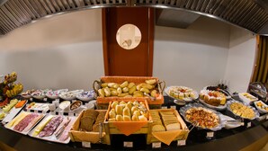 Un bufé con diversos alimentos, incluyendo panes, pasteles y embutidos.