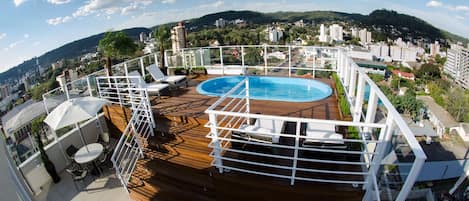 Una piscina al aire libre, sombrillas, sillones reclinables de piscina