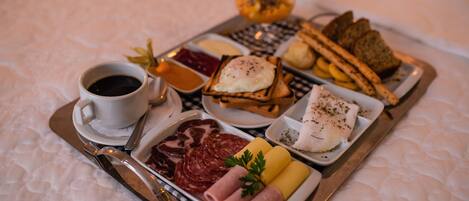 A breakfast tray with various foods including meats, eggs, bread, and beverages.
