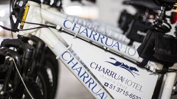 Una bicicleta con un letrero que dice "CHARRUA HOTEL" e información de contacto.