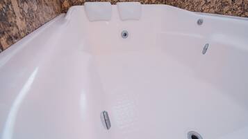 Eine weiße Badewanne mit zwei integrierten Sitzen und einem Ablass.