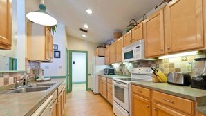 Una cocina con gabinetes de madera, microondas, estufa y lavaplatos.