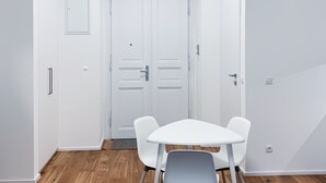 Ein Zimmer mit einer weißen Tür, einem weißen Tisch mit zwei Stühlen und Holzböden.