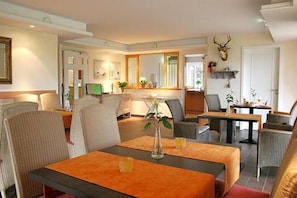 A hotel dining area with a long table, chairs, and a vase with flowers.