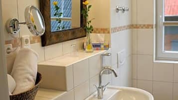 A bathroom with a white sink, a mirror, a towel rack, and a window.