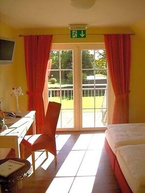 A hotel room with a bed, a desk, a chair, and a window with curtains.
