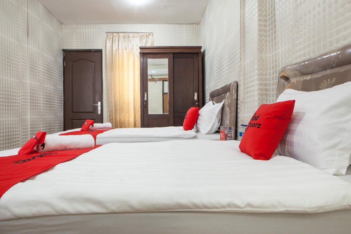 A hotel room with three beds, a wardrobe, and a door with a mirror.