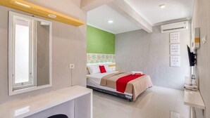 A modern hotel room with a bed, a mirror, a bedside table, and a small seating area. - Reddoorz Near Malioboro Tugu Station Jogja (Yogyakarta)