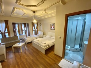 Une chambre d’hôtel avec deux lits, un canapé, une petite table et un espace douche.