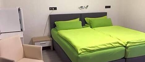 Une chambre à coucher comprenant un lit, une table de chevet, une chaise et une décoration florale fixée au mur.
