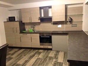 Una cocina moderna con armarios de madera, microondas, estufa y pileta.