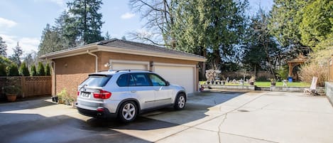A white SUV parked in a garage with a brick exterior and a covered patio area.