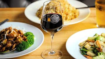 A dining table with three plates of food and a glass of red wine.