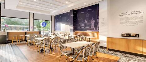 A modern dining area with wooden flooring, striped chairs, and a cityscape mural on the wall.