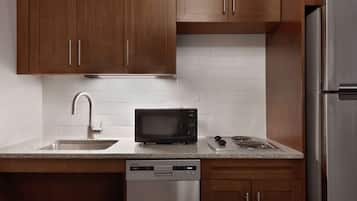 Una cocina compacta con armarios de madera, lavavajillas de acero inoxidable, microondas y estufa integrada.