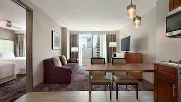 Une chambre d’hôtel comprenant un lit, un canapé, une table à manger avec des chaises, un coin cuisine avec un four à micro-ondes et une vue sur la ville par la fenêtre.