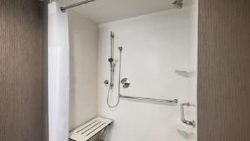 A shower area with a grab bar, a handheld showerhead, and a wall-mounted faucet.