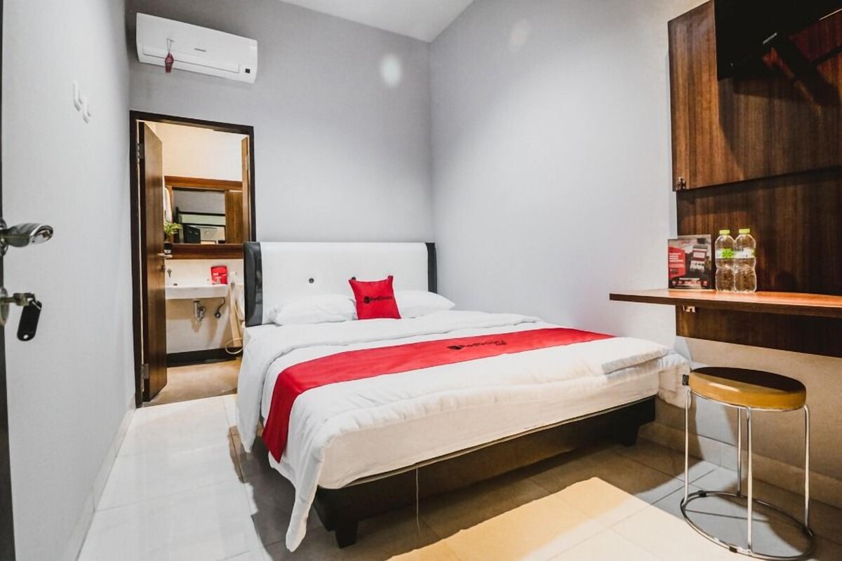 A modern bedroom with a bed, a small stool, a wooden cabinet, and a mirror.