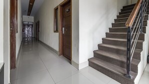 A hallway with a wooden door labeled "102" and a staircase with a metal railing. - RedDoorz near Mall Panakkukang 3 (Makassar)