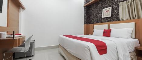 A hotel room with a bed, a desk, a chair, and a wall with a patterned design.