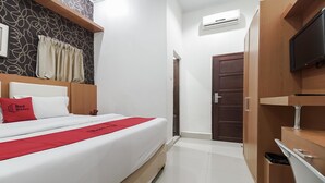 A hotel room with a bed, a wardrobe, a television, and an air conditioning unit. - RedDoorz near Mall Panakkukang 3 (Makassar)