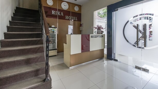 A hotel reception area with a staircase, clocks, and a reception desk. - RedDoorz near Mall Panakkukang 3 (Makassar)