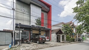 A building with a sign reading "RIKA HOTEL" and a parked car in front. - RedDoorz near Mall Panakkukang 3 (Makassar)