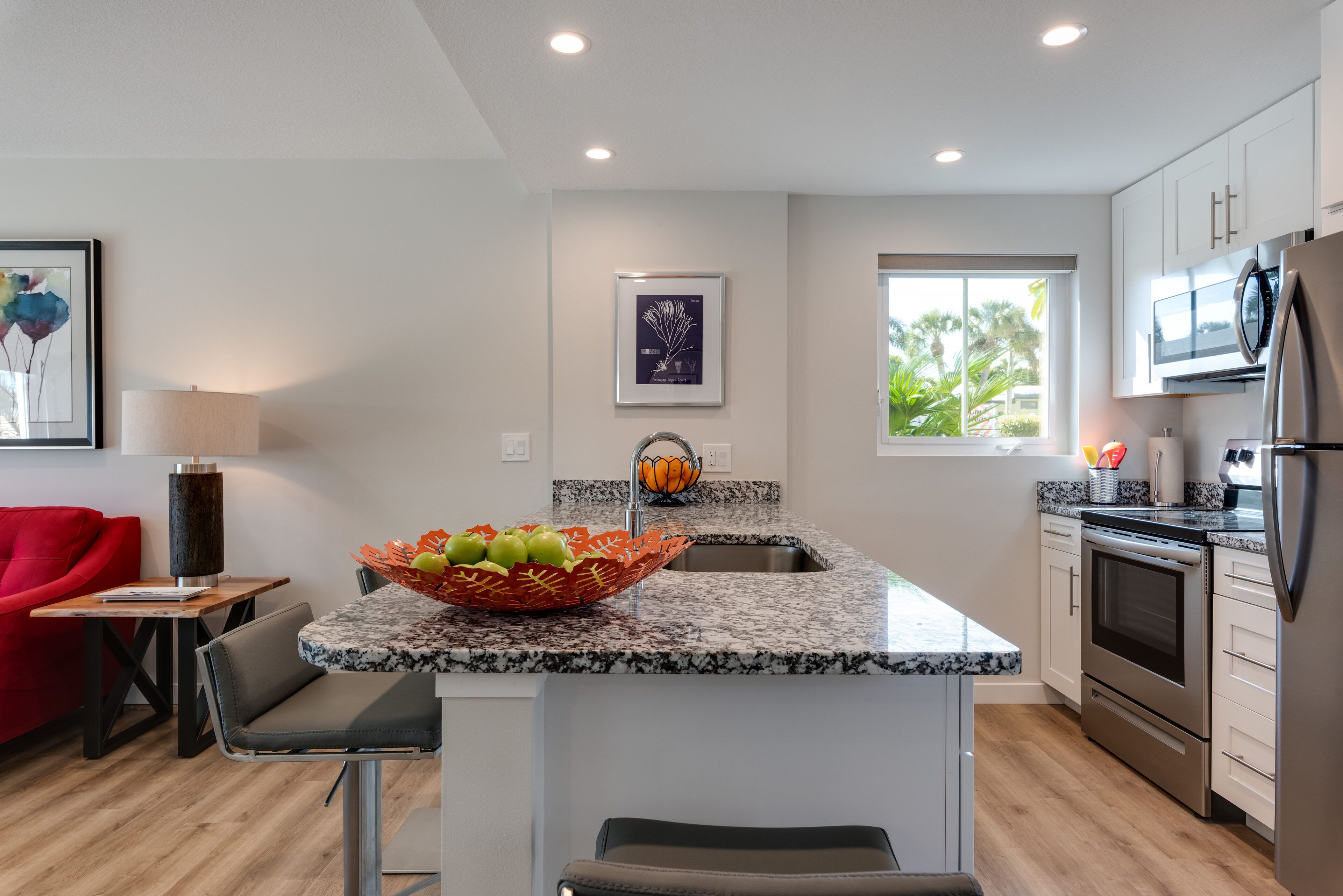 A modern kitchen with a granite countertop, stainless steel appliances, and a central island with a fruit bowl.