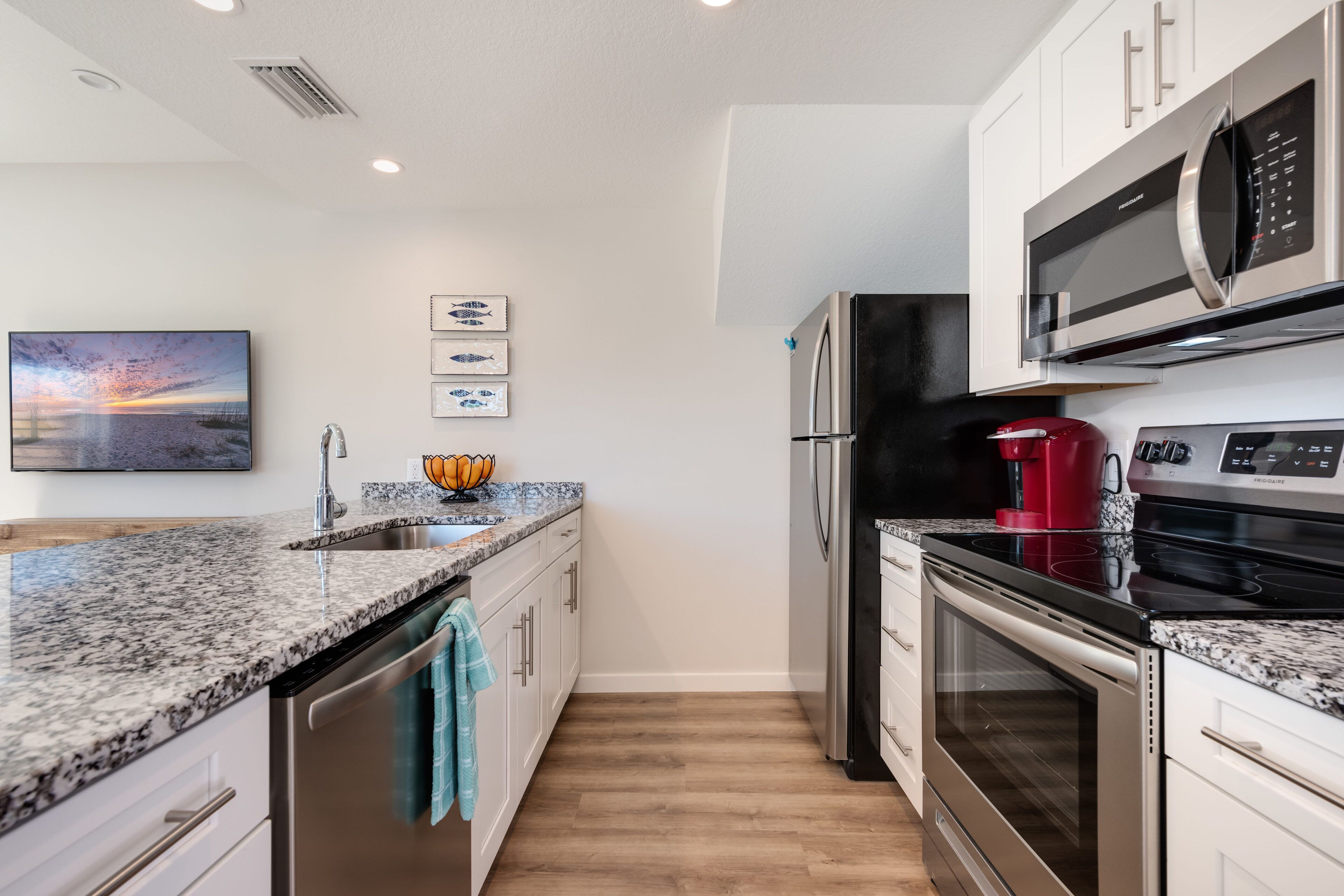 A modern kitchen with granite countertops, stainless steel appliances, and a wooden floor.